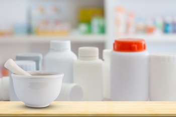 Mortar and pestle on pharmacy counter top with blur medicine shelves in drugstore background